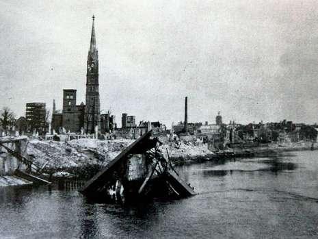 Dieses Bild zeigt die zerstörte Adolf Hitler-Brücke im April 1945. Dahinter die Stephani-Kirche